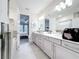 Open bathroom with dual sinks, marble countertops, gray cabinets, and a doorway leading to the main bedroom at 1003 Jack Nicklaus Ct, Kissimmee, FL 34747