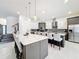 Contemporary kitchen features a large island with bar seating, pendant lights, and stainless steel appliances at 1003 Jack Nicklaus Ct, Kissimmee, FL 34747