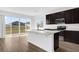 Stylish kitchen with dark cabinets, a large island with sink, stainless steel appliances, and sliding glass doors at 1209 Mattie Pointe Blvd, Auburndale, FL 33823