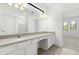 Double vanity with granite countertop, white cabinets, and mirrors in bathroom at 1242 Butterfly Orchid Rd, Davenport, FL 33837