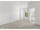 A bright bedroom with plush carpeting, a window, and an open doorway leading to the bathroom at 1242 Butterfly Orchid Rd, Davenport, FL 33837