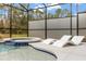 Close-up of a tranquil screened-in pool and spa with stylish lounge chairs at 1242 Butterfly Orchid Rd, Davenport, FL 33837