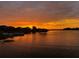 A picturesque sunset over a calm lake reflecting vibrant hues and distant silhouettes of homes at 16629 Broadwater Ave, Winter Garden, FL 34787