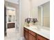 Bathroom with a large mirror, cherry-stained vanity, white sink, and doorway to another bathroom at 1720 Bridgets Ct, Kissimmee, FL 34744