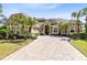 View of the home's front exterior, brick driveway, attached garage, and manicured tropical landscaping at 1720 Bridgets Ct, Kissimmee, FL 34744