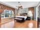 Spacious bedroom with wood floors, a ceiling fan, decorative curtains, and a view of the yard at 1720 Bridgets Ct, Kissimmee, FL 34744