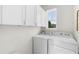 Well-lit laundry room featuring overhead cabinets and a side by side washer and dryer at 17398 Blazing Star Cir, Clermont, FL 34714