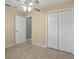 This bedroom features neutral walls, ceiling fan, tile floor, and a double closet with white doors at 2200 Pine Needle Trl, Kissimmee, FL 34746