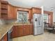 Well-equipped kitchen featuring stainless steel refrigerator and wooden cabinets at 2200 Pine Needle Trl, Kissimmee, FL 34746