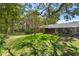 The backyard features lush green grass and mature trees providing ample shade at 2723 Beacon St, Eustis, FL 32726