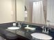 Well-lit bathroom features a double sink vanity, a large mirror, and shower with a white curtain at 3000 Maingate Ln # 227, Kissimmee, FL 34747