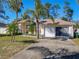 Traditional single-story home featuring a two-car garage and mature landscaping with palm trees at 3252 Noah St, Deltona, FL 32738