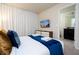 Well-lit bedroom with white bed, blue accents, stylish nightstands, TV and ensuite bathroom at 3428 Lilac Way, Davenport, FL 33897