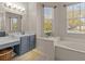 Bright bathroom featuring a vanity with gray cabinets, white countertop, and a soaking tub by a window at 5325 Cypress Reserve Pl, Winter Park, FL 32792