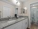 Bathroom featuring dual sinks with granite counters, white cabinetry, and a shower at 5325 Cypress Reserve Pl, Winter Park, FL 32792