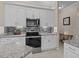 Kitchen featuring stainless oven, microwave, granite counters, tile backsplash, and white cabinets at 5325 Cypress Reserve Pl, Winter Park, FL 32792