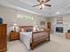Spacious main bedroom with a ceiling fan, tray ceiling, fireplace, and neutral decor at 5325 Cypress Reserve Pl, Winter Park, FL 32792