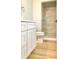 Modern bathroom with tiled walk-in shower, white vanity, and warm-toned laminate floors at 5830 Beechmont Blvd, Orlando, FL 32808