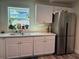 Bright kitchen featuring white cabinets, stainless steel refrigerator, and a large window at 655 Katherine Ave, Orlando, FL 32810