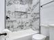 Bathroom with white bathtub and shower featuring stylish marble-patterned tile and dark fixtures at 709 S Parsons Ave, Deland, FL 32720