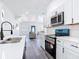 Contemporary kitchen boasts stainless steel appliances, white cabinets, and seamless access to the living area at 709 S Parsons Ave, Deland, FL 32720