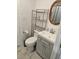 Cozy bathroom featuring tile flooring, grey vanity, toilet, shelving, and round decorative mirror at 723 Dougherty St, New Smyrna Beach, FL 32168