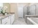Well-appointed bathroom featuring dual sinks, granite countertops, a separate tub, and a glass-enclosed shower at 7376 Oakmoss Loop, Davenport, FL 33837
