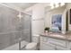 Clean bathroom featuring a walk-in shower with a sliding door, vanity, and mirror at 7376 Oakmoss Loop, Davenport, FL 33837