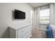 Well-lit bedroom featuring a TV, dresser, and large window with window treatments at 7376 Oakmoss Loop, Davenport, FL 33837