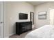 Well-lit bedroom featuring a dresser, TV, mirror, and appealing modern decor at 7376 Oakmoss Loop, Davenport, FL 33837