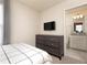 Bedroom featuring a dark dresser with a TV and an ensuite bathroom with granite vanity at 7376 Oakmoss Loop, Davenport, FL 33837