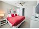 Bright bedroom with a queen bed, red and white patterned comforter, and a mirrored dresser complemented by neutral walls at 7719 Graben St, Kissimmee, FL 34747