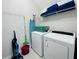 Functional laundry room featuring a washer, dryer, ironing board, storage racks, and essential cleaning supplies at 7719 Graben St, Kissimmee, FL 34747