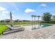 Backyard pool and patio with lounge chairs and palm trees against a sunny sky at 8025 Topsail Pl, Winter Garden, FL 34787
