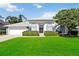 Charming single-story home boasts a lush lawn and manicured hedges framing arched windows at 824 Palm Cove Dr, Orlando, FL 32835
