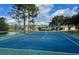 Community tennis court with well-maintained surface, surrounded by mature trees and a pond at 9102 Shadowbrook Trl, Orlando, FL 32825