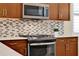 Close-up of kitchen details with stainless steel appliances, modern backsplash, and wood cabinetry at 937 Avery Meadows Way, Deland, FL 32724
