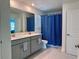 This bathroom has a double sink vanity, a large mirror, a tiled floor, and a blue shower curtain at 9787 Introduction Way, Orlando, FL 32832
