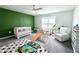 This colorful bedroom has a green accent wall, a ceiling fan, a window with blinds, and a white chair at 9787 Introduction Way, Orlando, FL 32832
