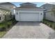 Paver driveway leading to a two-car garage with manicured landscaping at 9787 Introduction Way, Orlando, FL 32832