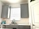 Well-lit kitchen with stainless steel faucet, sleek gray cabinets, and a modern tiled backsplash at 9787 Introduction Way, Orlando, FL 32832