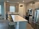Modern kitchen with stainless steel appliances, gray cabinetry, and a spacious quartz island with seating at 9787 Introduction Way, Orlando, FL 32832