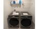 This laundry room has a washer and dryer with a shelf above, a tiled floor, and white walls at 9787 Introduction Way, Orlando, FL 32832