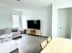 A bright living room featuring a modern entertainment center and dining table with wood-look flooring at 9787 Introduction Way, Orlando, FL 32832