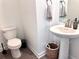 Bright powder room featuring a pedestal sink, toilet, decorative mirror, and wood-style flooring at 9787 Introduction Way, Orlando, FL 32832