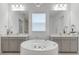 Bright bathroom featuring a round soaking tub, dual vanities, large mirrors, and stylish light fixtures at 10032 Brocksport Cir, Gotha, FL 34734