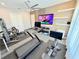 Well-equipped home gym with treadmill, cycling machine, TV, weights, and fan for a complete workout experience at 10032 Brocksport Cir, Gotha, FL 34734