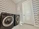 Modern laundry room featuring a front-loading washer and dryer set, complemented by stylish wallpaper and tile flooring at 10032 Brocksport Cir, Gotha, FL 34734