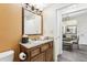 Well-lit bathroom with a vanity featuring granite countertop, decorative mirror, and view into dining area at 12527 Floridays Resort Dr # E-111, Orlando, FL 32821