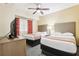 Inviting bedroom with two queen beds, decorative curtains, a ceiling fan, and neutral walls at 12527 Floridays Resort Dr # E-111, Orlando, FL 32821